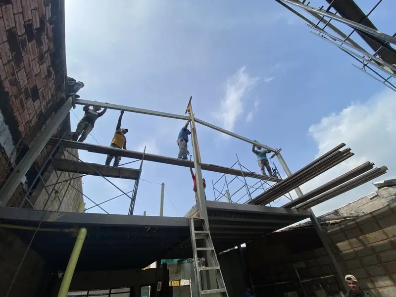 Cuadrilla ensamblando cerchas metálicas sobre andamios